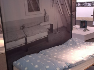 Postel i s povlečením, na kterém jsou vločky a písmeno J.