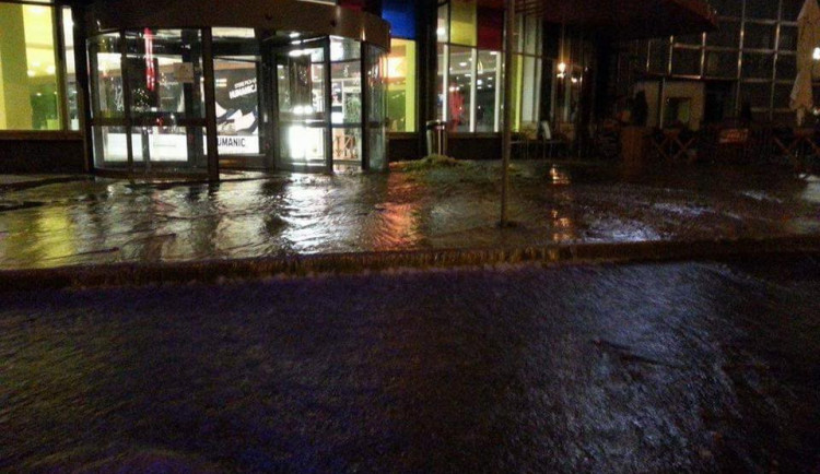 Voda z prasklého potrubí u OC Nisa zaplavila vchod i silnici u nákupního centra