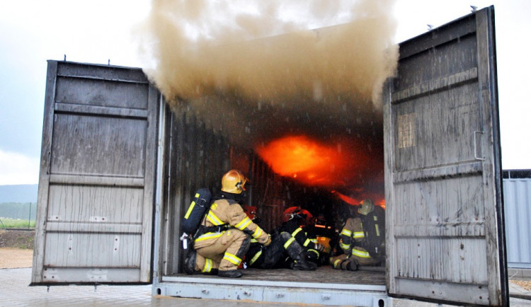 Plameny šlehají až ven z kontejneru.