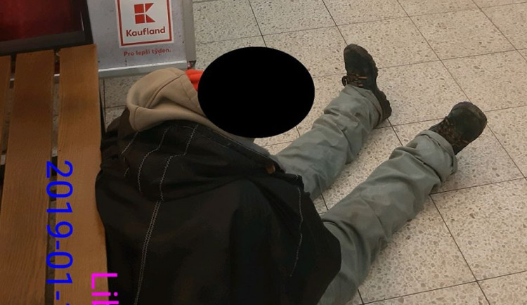 Bezdomovec usnul za pokladnami na zemi.