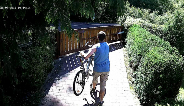 Muž odnáší kolo ze zahrady.