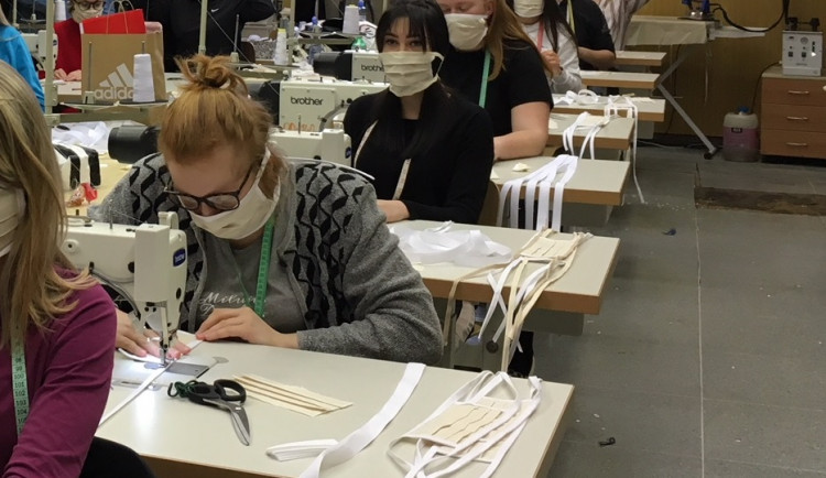 Studenti i pedagogové tvoří roušky.