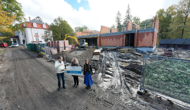 Předání šeku u rozestaveného pavilonu školy.