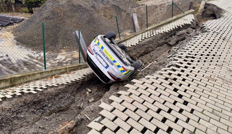 U stavby v Praze se utrhl svah i s autem městské policie, skončilo na střeše