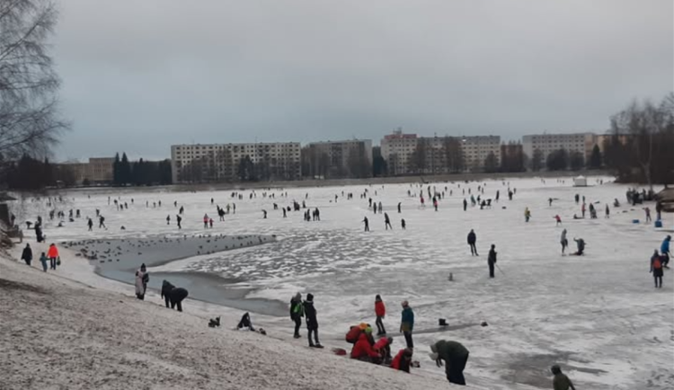 Snímek zamrzlé přehrady Mšeno v Jablonci nad Nisou s bruslaři