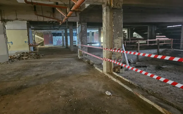 Demolice vnitřních konstrukcí – odhalené nosné sloupy, částečně odstraněné podlahové vrstvy. Plocha je zabezpečena páskami kvůli bezpečnosti pracovníků.