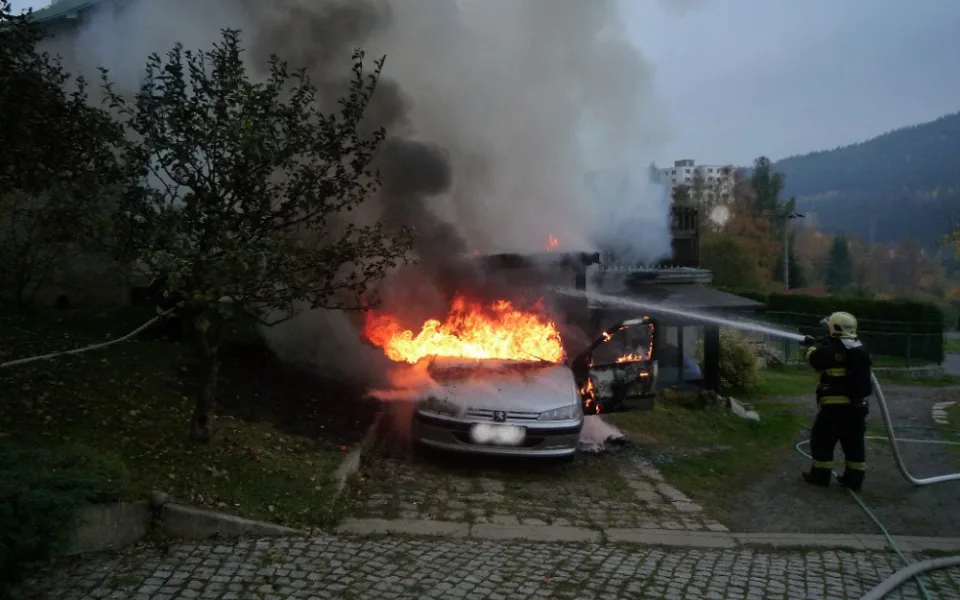 Hořící auto a přístavek.