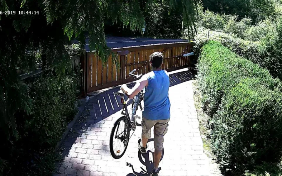 Muž odnáší kolo ze zahrady.