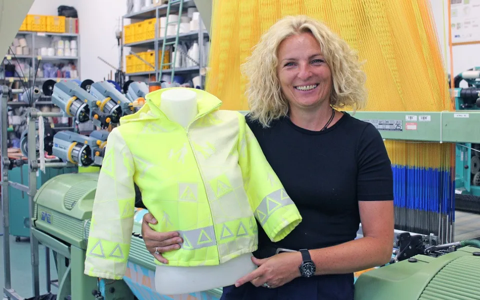 Brigita Kolčavová u tkacího stroje s elektronickými žakárskými prošlupními mechanismy a s prototypem vesty s bezpečnostními prvky
