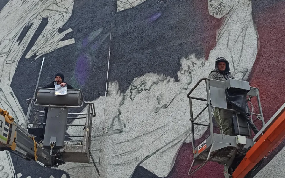 Na zeď domu designéři Jiří Hořavka a Ondřej Beneš sprejují obří obraz skleněného draka.