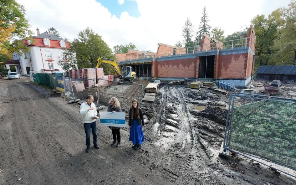 Předání šeku u rozestaveného pavilonu školy.