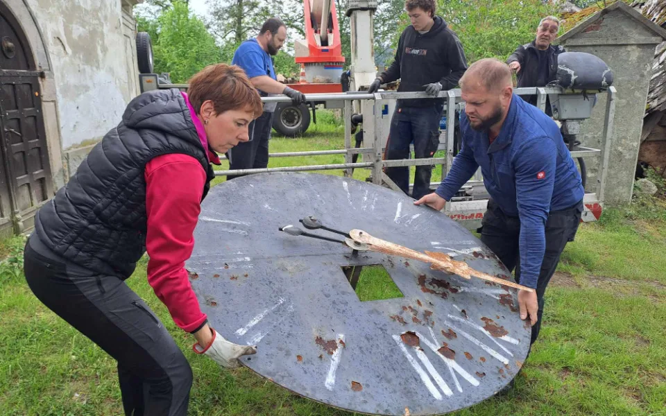 Hodinářka Marie Nesnídalo s kolegy při snášení jednoho z ciferníků.