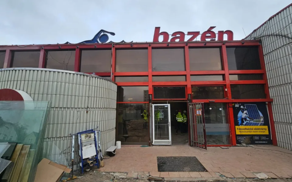 Exteriér bazénu – čelní část objektu má odstraněné vstupní dveře a část fasády. Zahájila se demontáž opláštění budovy. Zmizela také charakteristická "vlnka" nad vstupem, která však nebyla součástí původního návrhu bazénu.